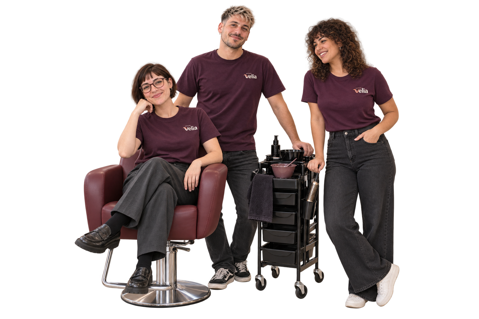 Mila, Leo und Sara gemeinsam am Salonstuhl und Farbtrolley, mit modernen Frisuren und kleinen Velia-Logos auf ihren Arbeitsshirts
